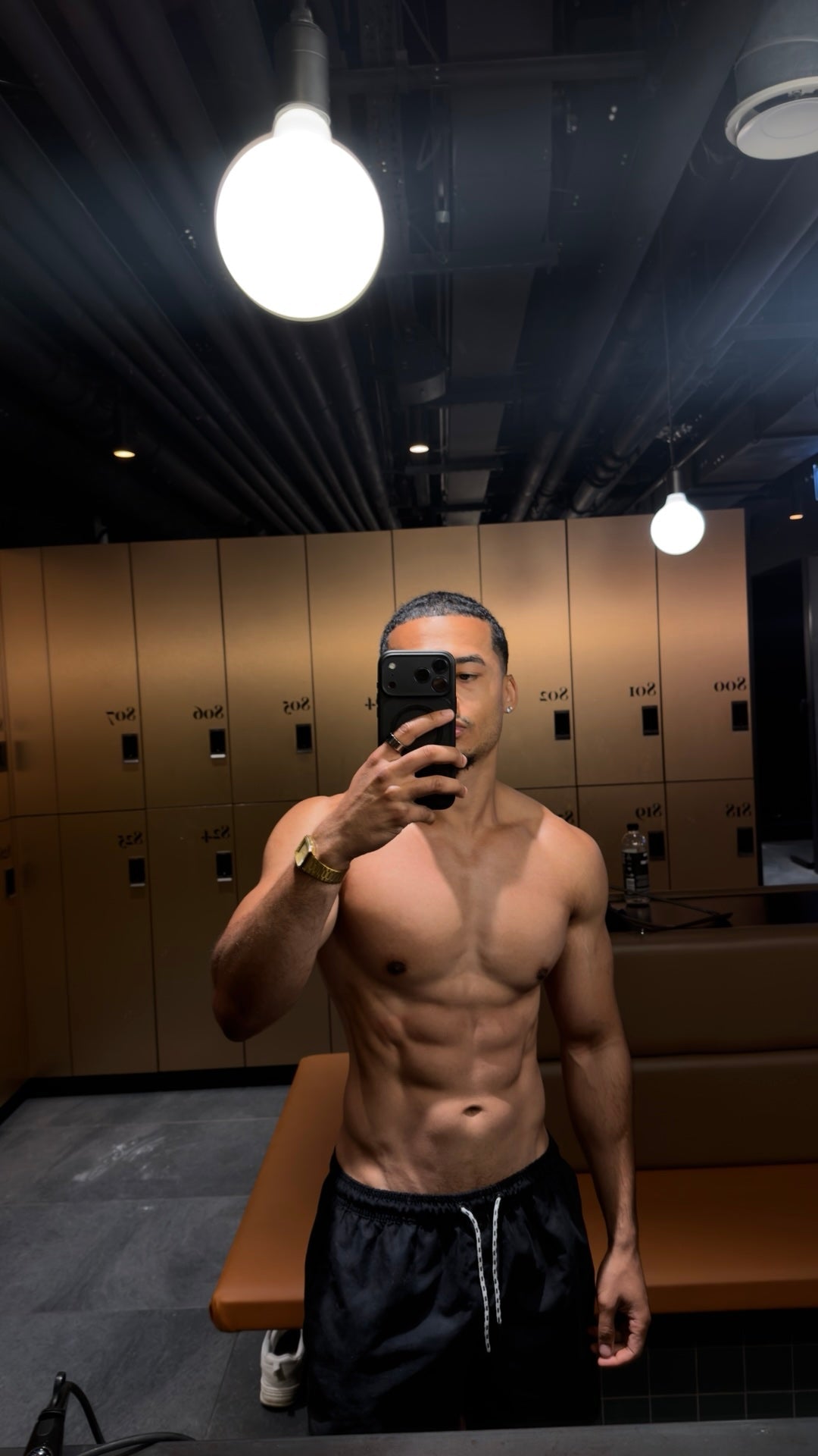 Nathan Lawrence in a gym locker room showing his hybrid-trained physique
